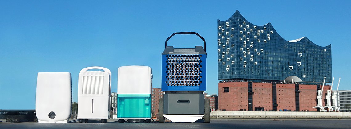 Vier verschiedene Luftentfeuchter von Fieberitz stehen vor der Elbphilharmonie in Hamburg bei strahlend schönem Wetter.